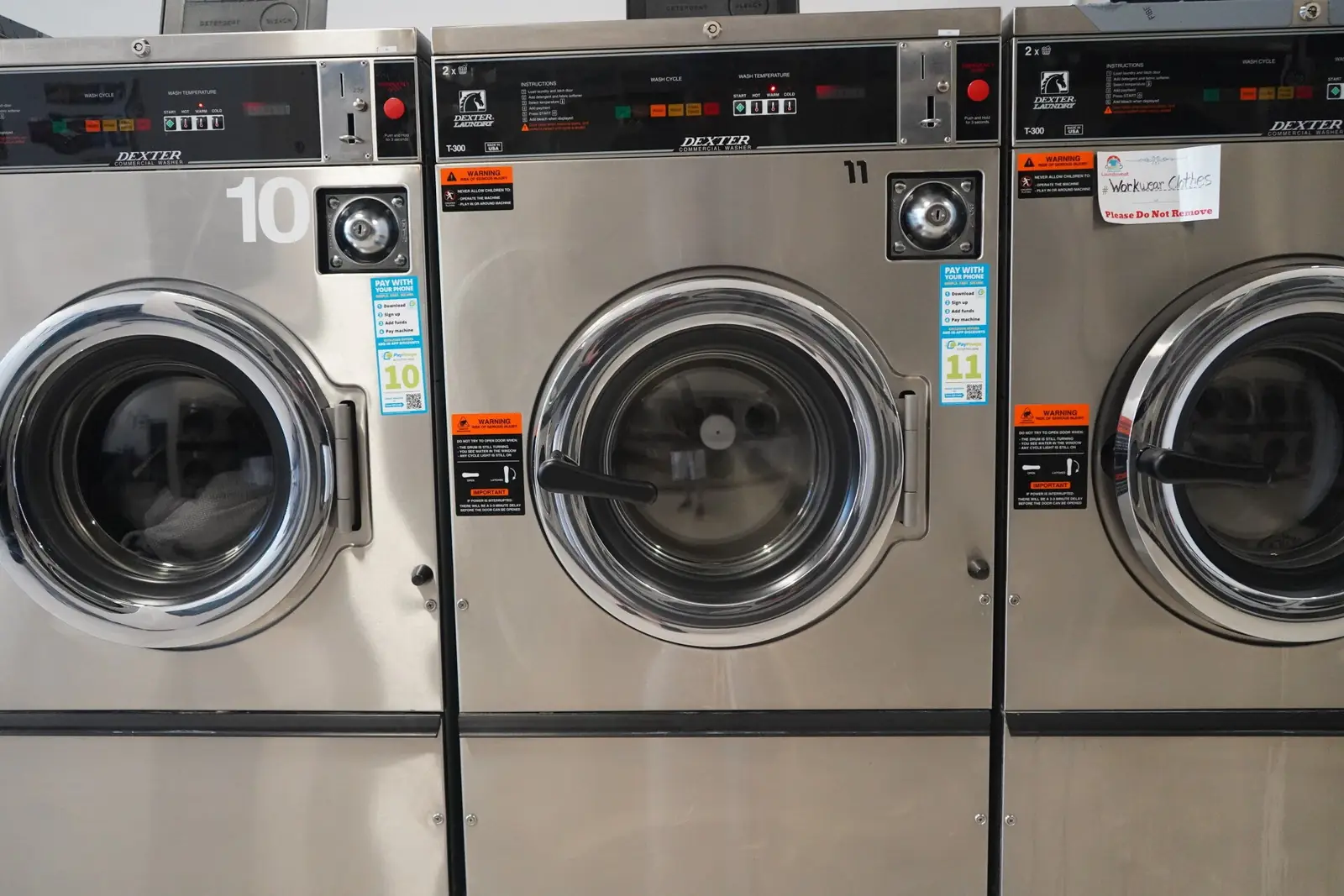 Three stainless-steel Dexter front-load washers, numbered 10 and 11, inside Beaumont Laundromat